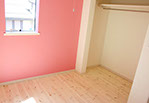 ピンクの壁と優しい色の無垢材の明るい子供部屋