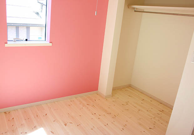 ピンクの壁と優しい色の無垢材の子供部屋